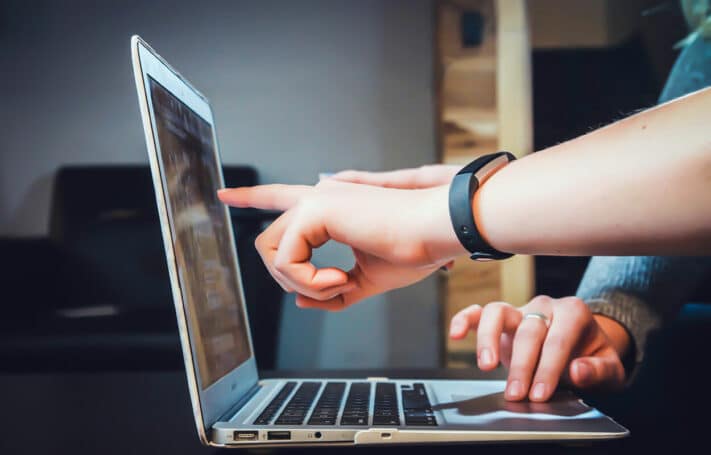 Des mains pointent vers un écran d'ordinateur, illustrant l'impact de la vidéo marketing pour générer des leads.